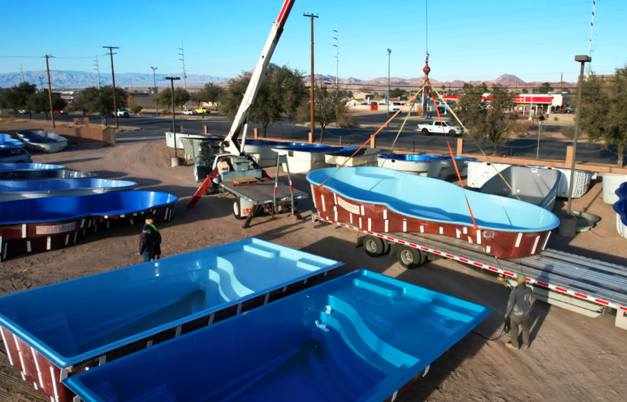 Crane setting a fiberglass pool shell into a backyard